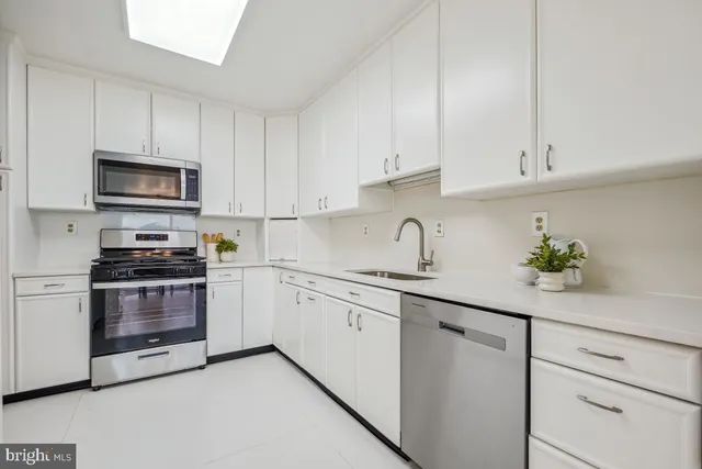 a kitchen with granite countertop white cabinets and stainless steel appliances