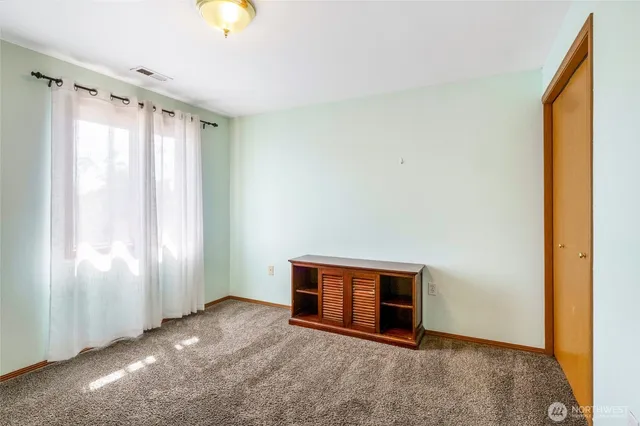 a view of an empty room with window and closet area