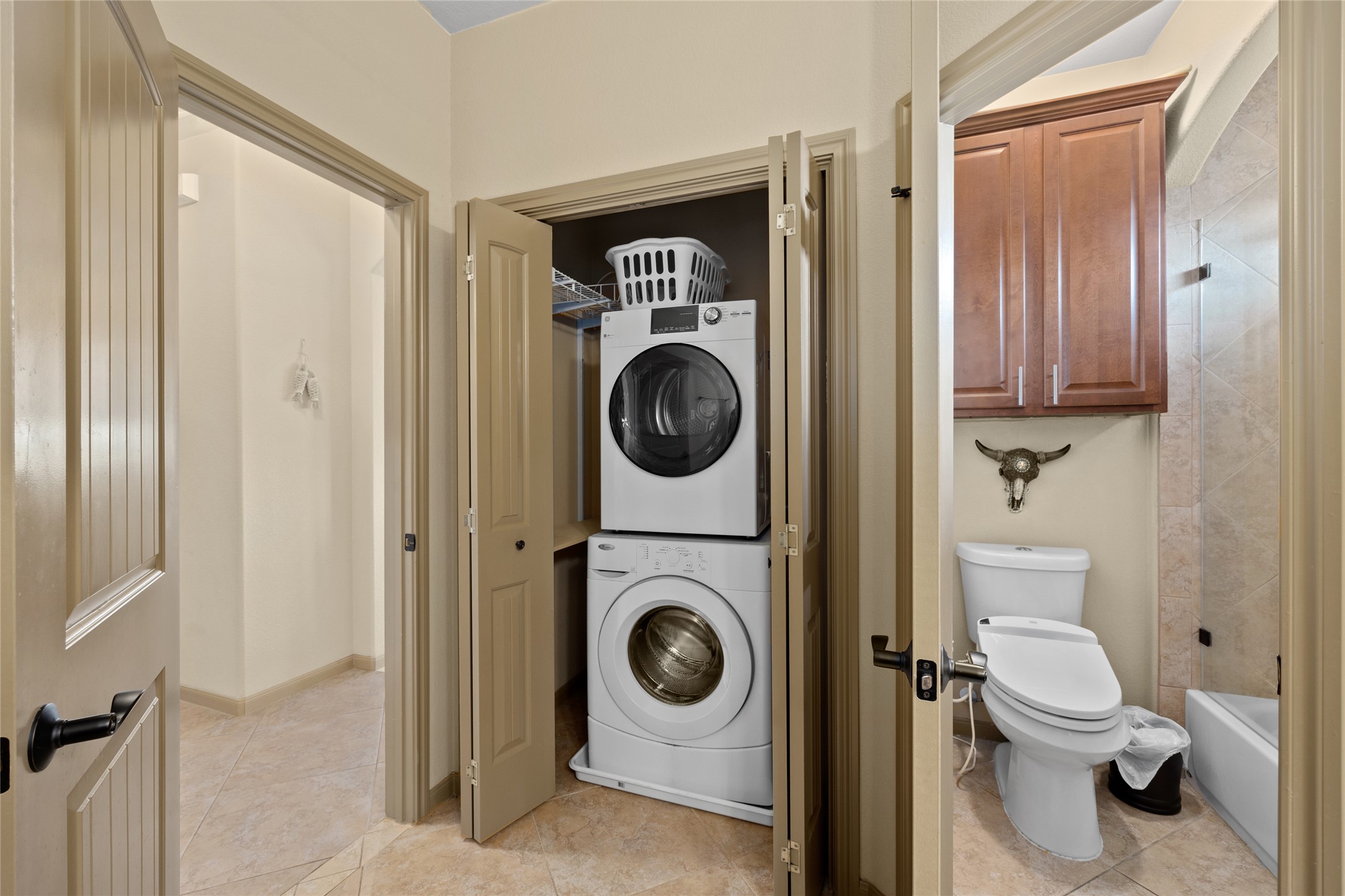 1690 Hickory Creek Road Marble Falls, TX 78654 - Photo 13 of 25 Full bath with stacked washing machine and dryer, light tile patterned floors, and bathtub / shower combination