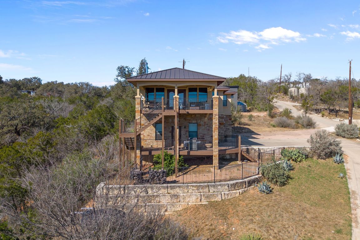 1690 Hickory Creek Road Marble Falls, TX 78654 - Photo 22 of 25 Rear view of house featuring stone siding, stairway, a metal roof, a standing seam roof, and a balcony