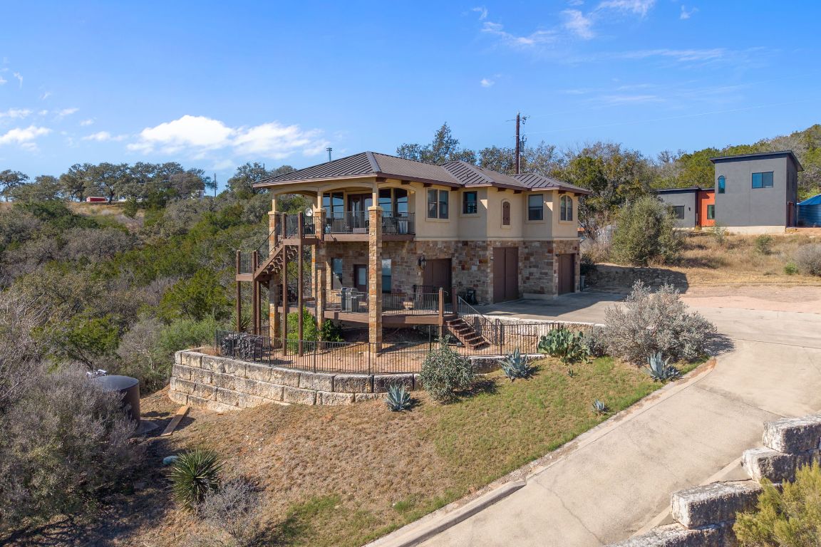 1690 Hickory Creek Road Marble Falls, TX 78654 - Photo 23 of 25 View of front facade with stairway, stone siding, concrete driveway, stucco siding, and a wooden deck