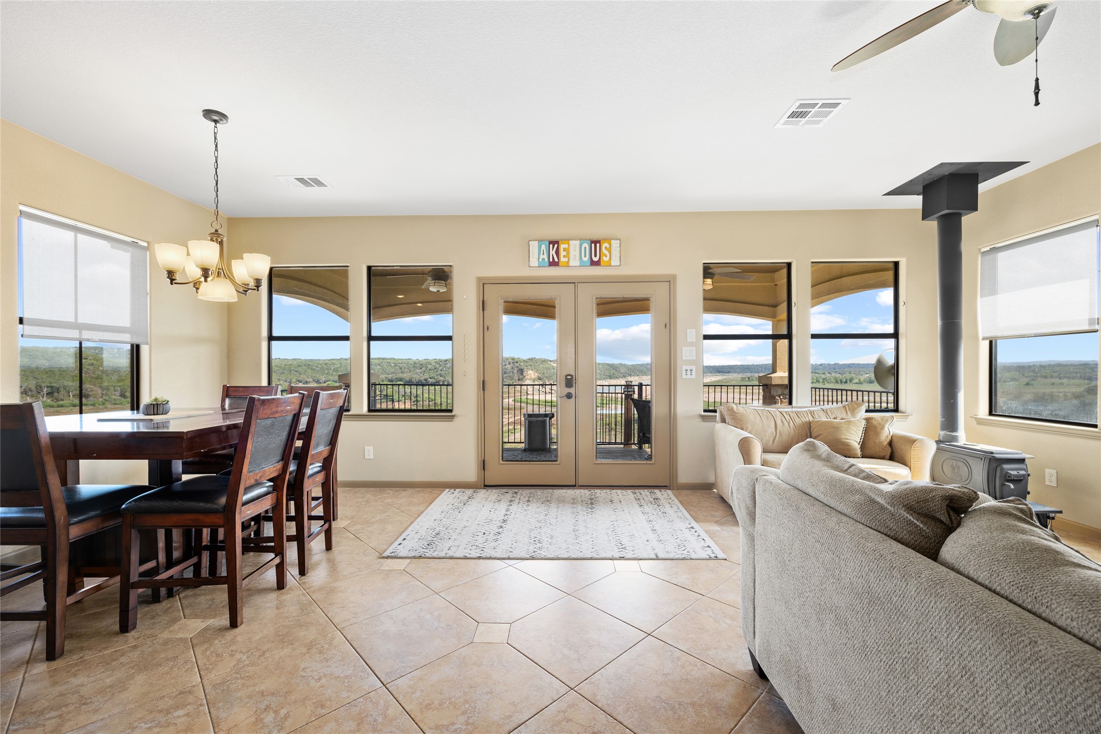1690 Hickory Creek Road Marble Falls, TX 78654 - Photo 4 of 25 Dining area with a wood stove, healthy amount of natural light, a ceiling fan, and light tile patterned floors