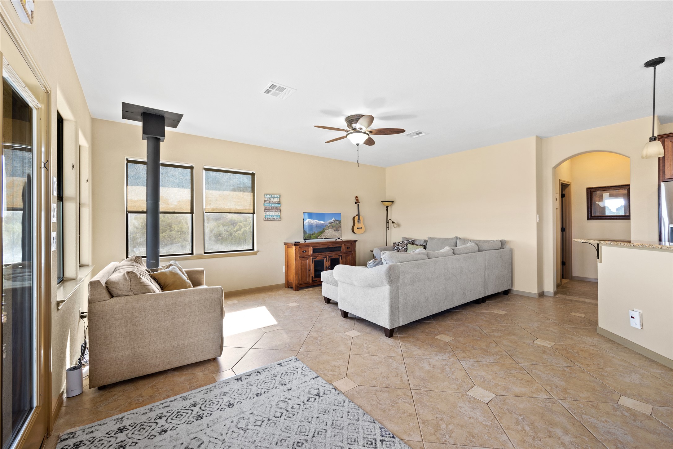 1690 Hickory Creek Road Marble Falls, TX 78654 - Photo 5 of 25 Living room with a wood stove, ceiling fan, arched walkways, and light tile patterned floors
