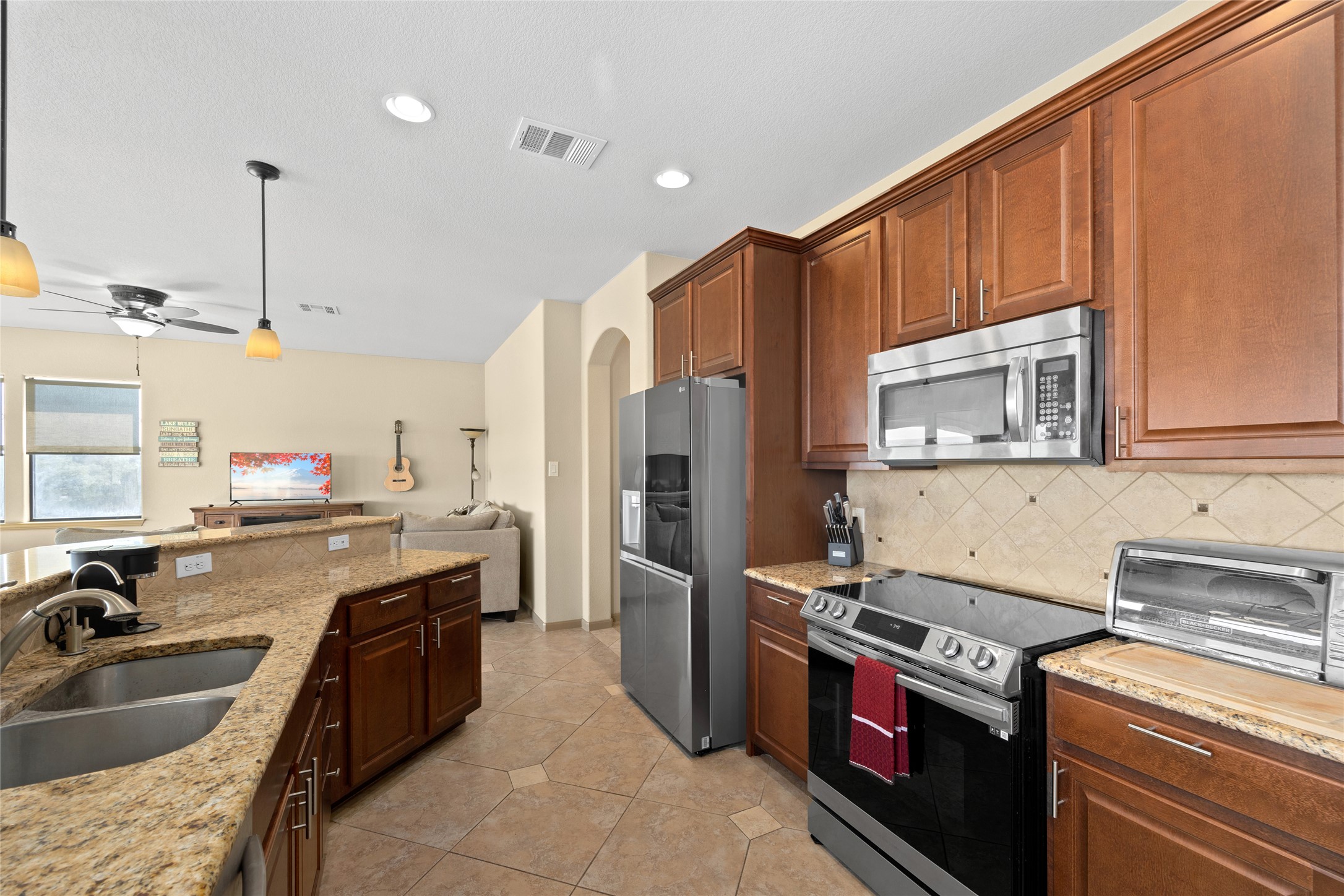 1690 Hickory Creek Road Marble Falls, TX 78654 - Photo 24 of 25 Kitchen featuring appliances with stainless steel finishes, pendant lighting, light stone countertops, open floor plan, and ceiling fan