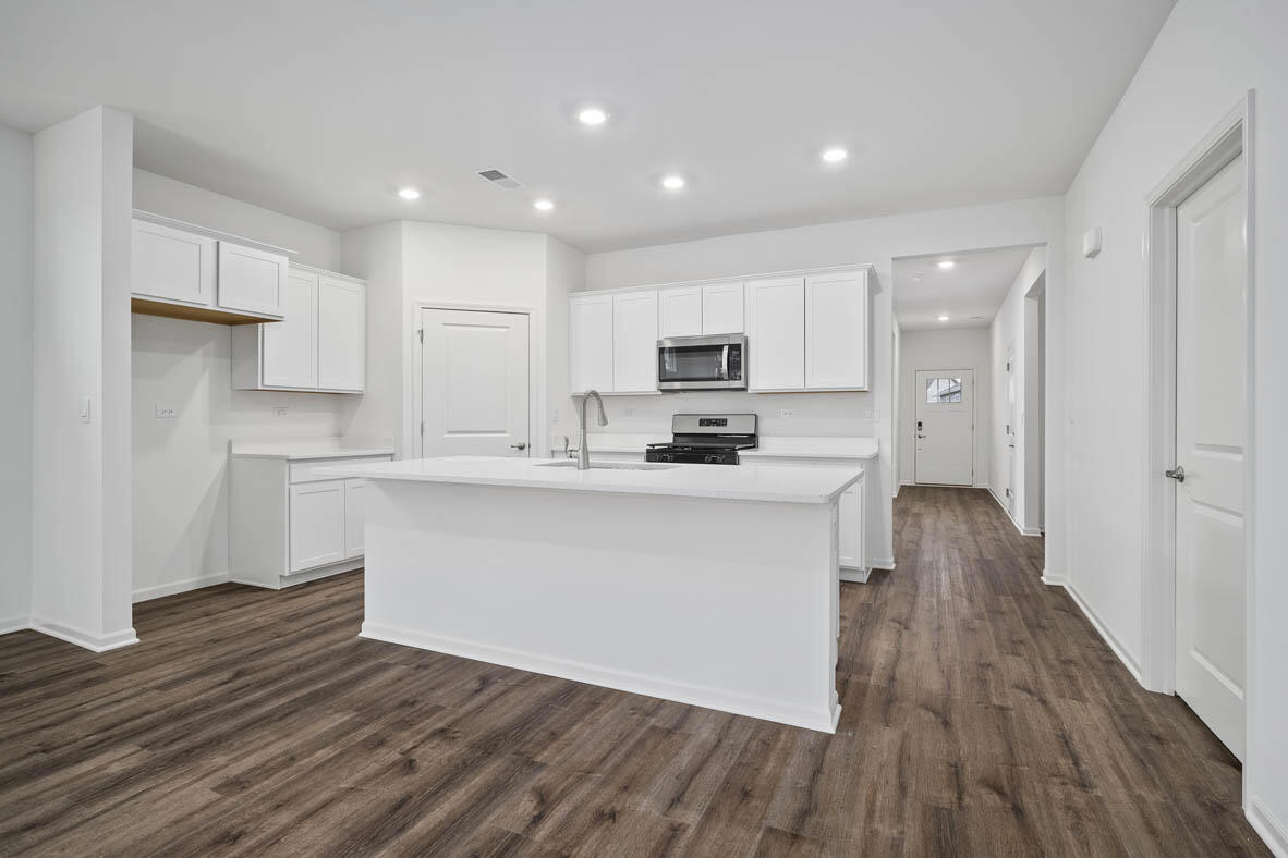 7676 West 106th Place Crown Point, IN 46307 - Photo 5 of 13 a kitchen with wooden floors white cabinets and stainless steel appliances