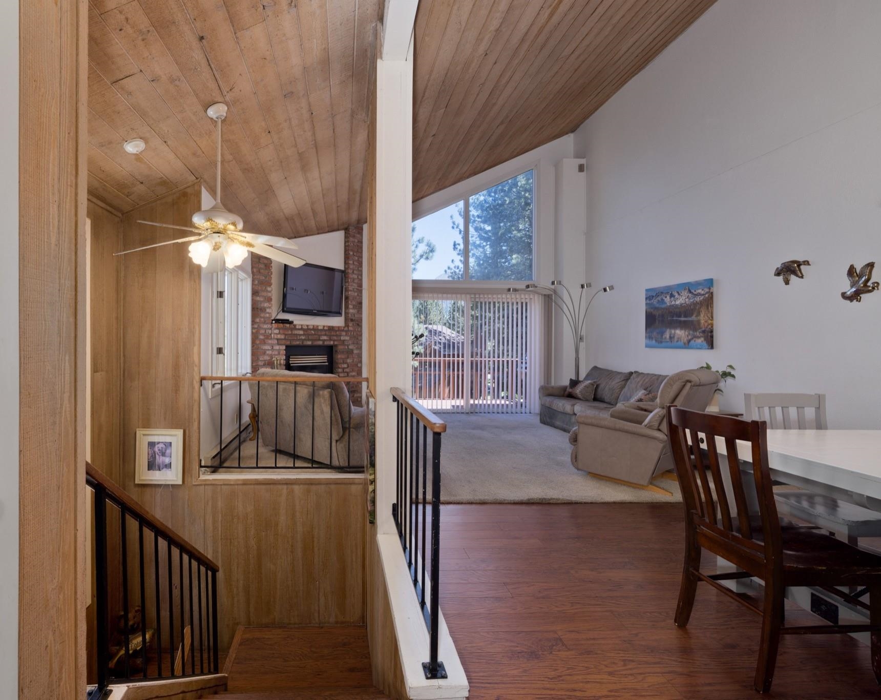 3392 Chateau Road, Unit 29 Mammoth Lakes, CA 93546 - Photo 14 of 30 Vaulted ceiling with wood-finish planks, accent brick fireplace, wood-finish flooring, and a large triangular window