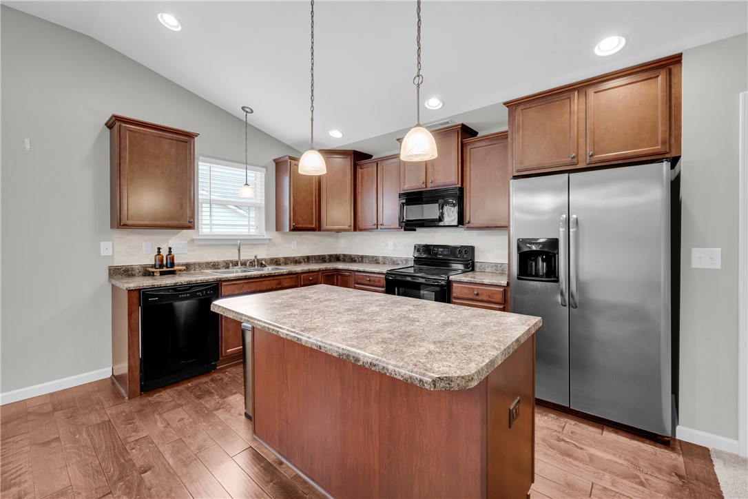 138 Madison Pointe Drive Seneca, SC 29678 - Photo 12 of 42 This functional kitchen features rich cabinetry, modern appliances, and a convenient island with pendant lighting.