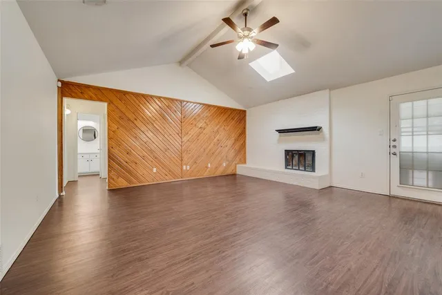 an empty room with wooden floor fireplace and windows