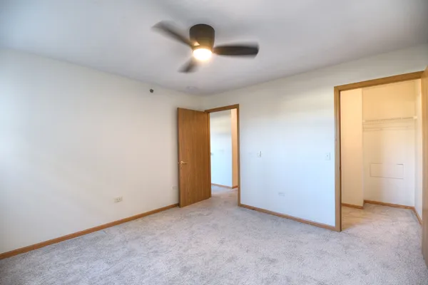 an empty room with chandelier fan and windows