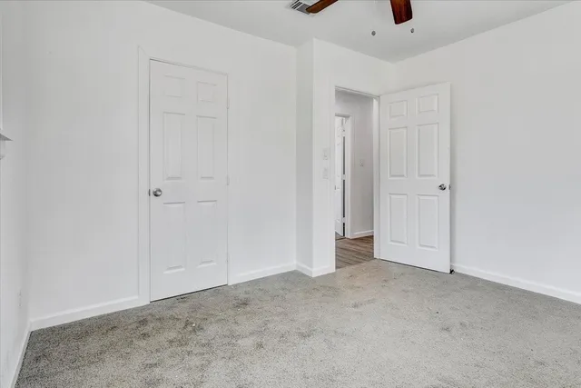 an empty room with windows and ceiling fan