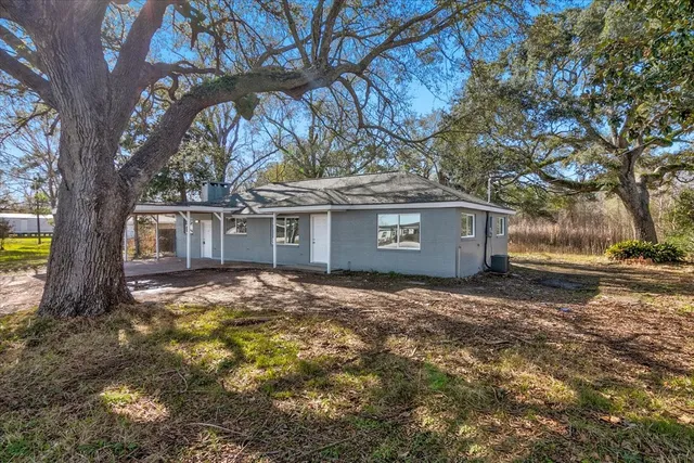 a view of a house with a yard and large tree