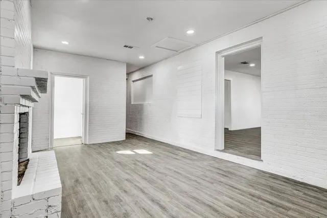 an empty room with wooden floor and a fireplace