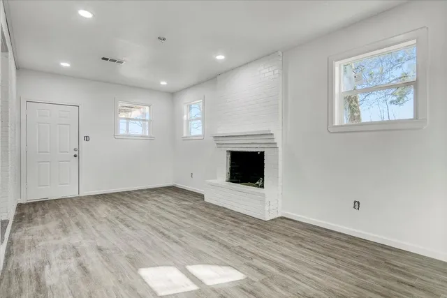 a view of empty room with wooden floor and fireplace