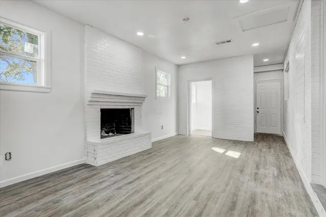 an empty room with wooden floor and fireplace