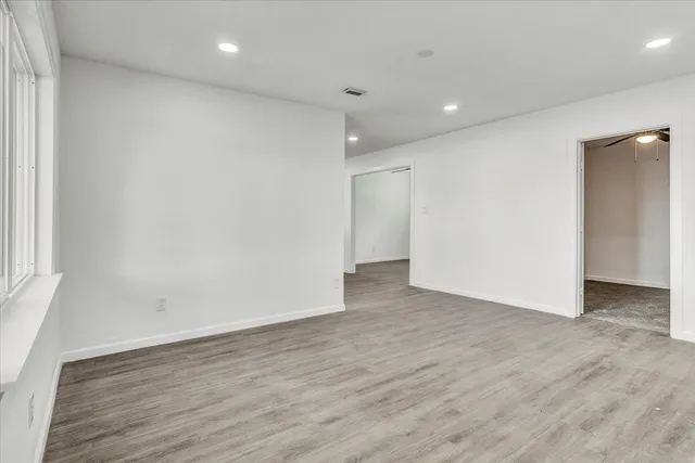 an empty room with wooden floor and windows
