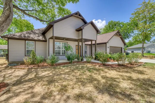 a view of a house with a yard and large tree