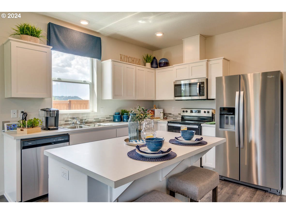 2228 30th Place Springfield, OR 97477 - Photo 9 of 20 a kitchen with stainless steel appliances a sink a stove a refrigerator cabinets and a window