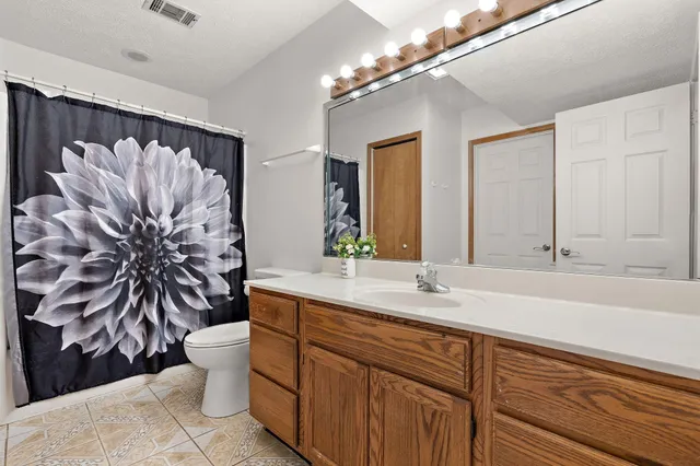 a bathroom with a granite countertop sink a toilet and a mirror