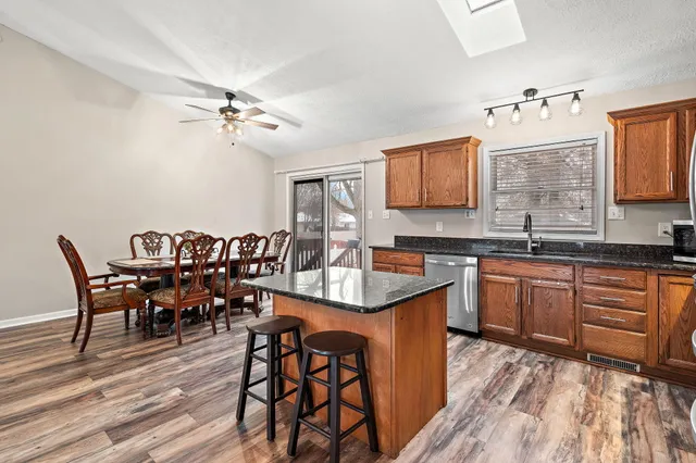 a kitchen with stainless steel appliances granite countertop a sink a stove a dining table and chairs