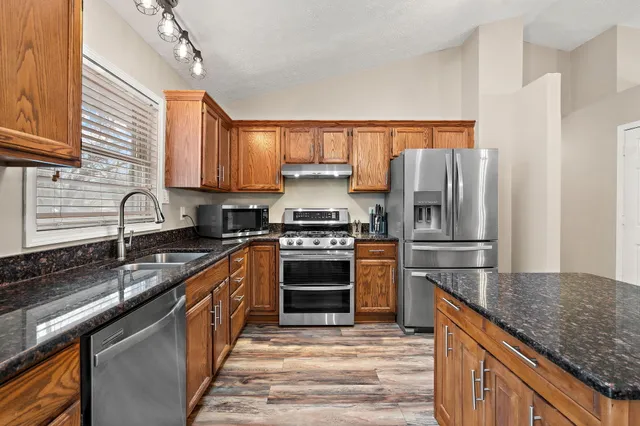 a kitchen with granite countertop a stove sink and refrigerator