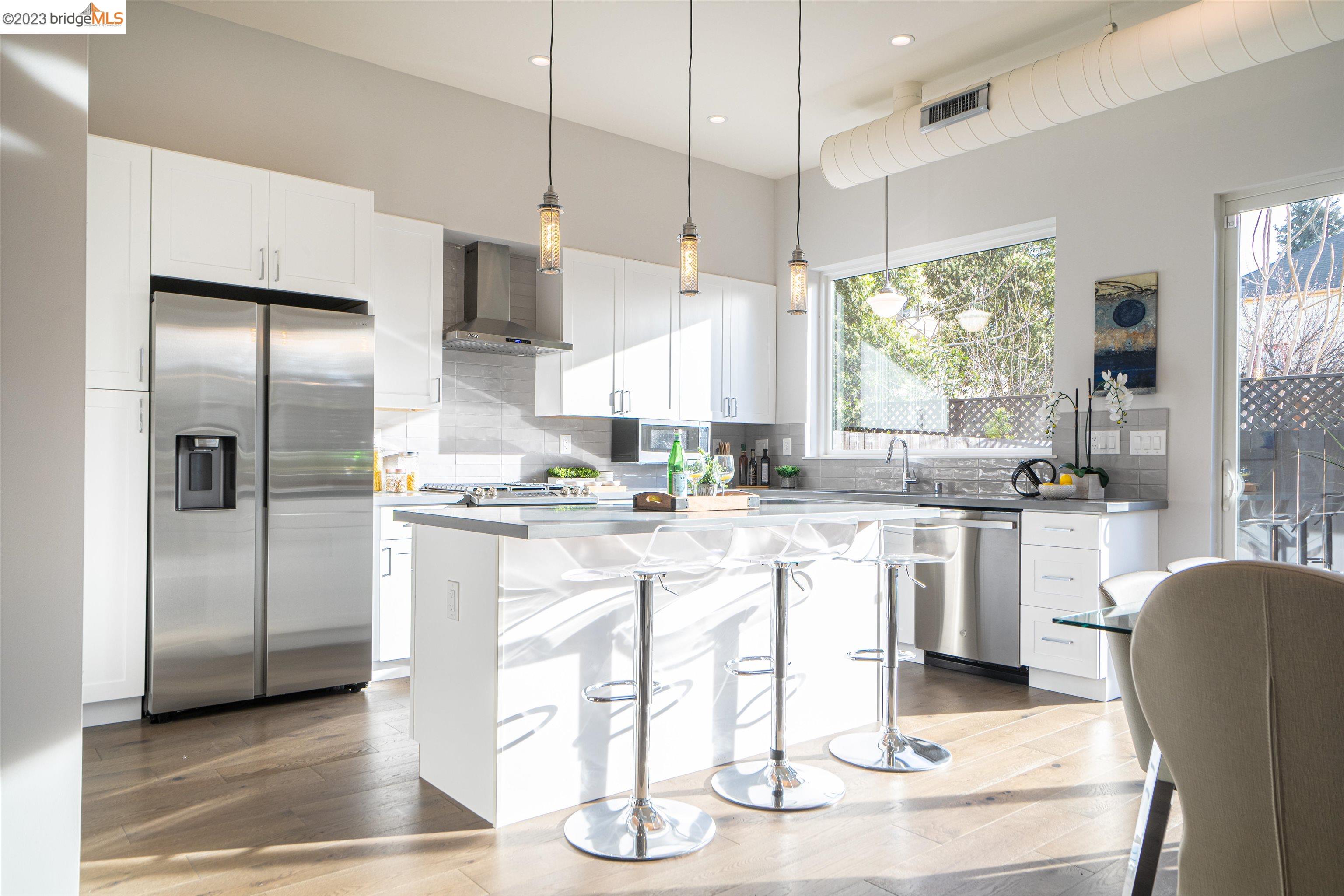 1679 12th Street Oakland, CA 94607 - Photo 5 of 26 a kitchen with stainless steel appliances granite countertop a refrigerator a sink a stove and white cabinets with wooden floor