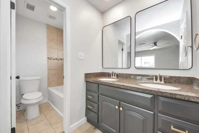 a bathroom with a granite countertop sink a toilet and a mirror