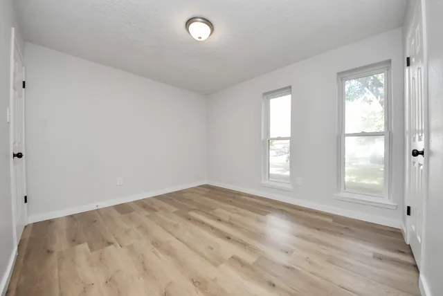 an empty room with wooden floor and windows