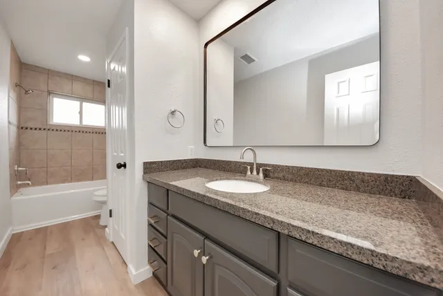 a bathroom with a granite countertop sink and a bathtub