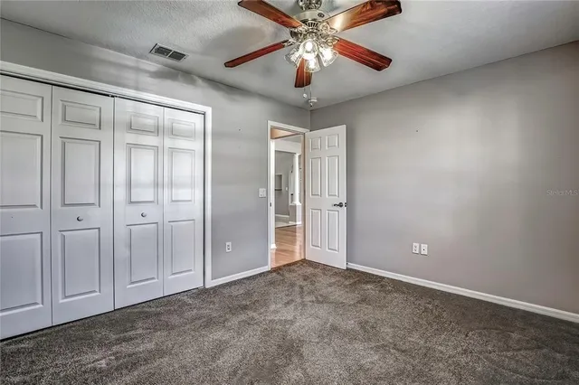 an empty room with closet and a chandelier fan