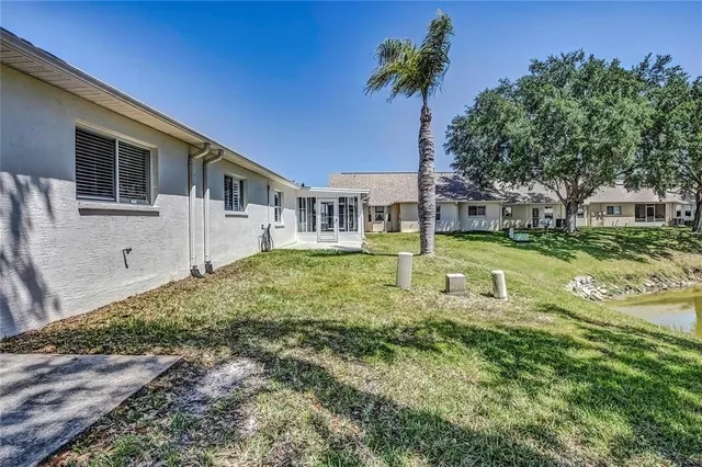 a backyard of a house with table and chairs under an umbrella
