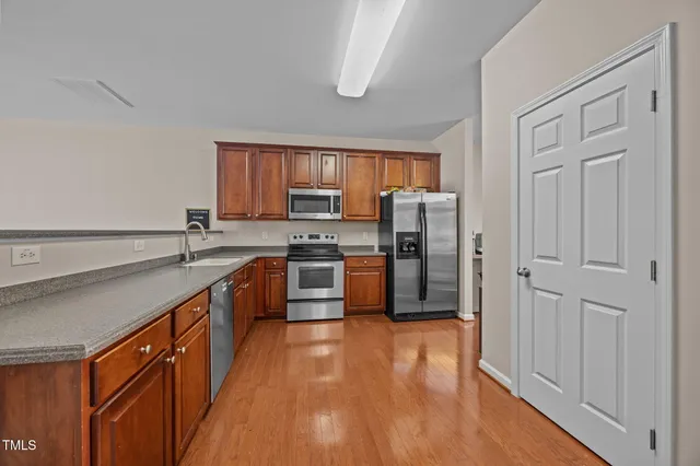 a kitchen with stainless steel appliances granite countertop a refrigerator a sink dishwasher a stove with wooden floor and cabinets