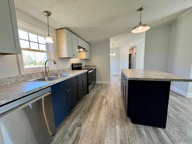 a large kitchen with granite countertop a sink dishwasher a stove and a refrigerator