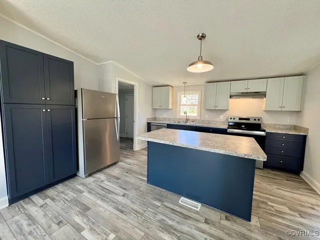 a kitchen with granite countertop wooden cabinets and a refrigerator