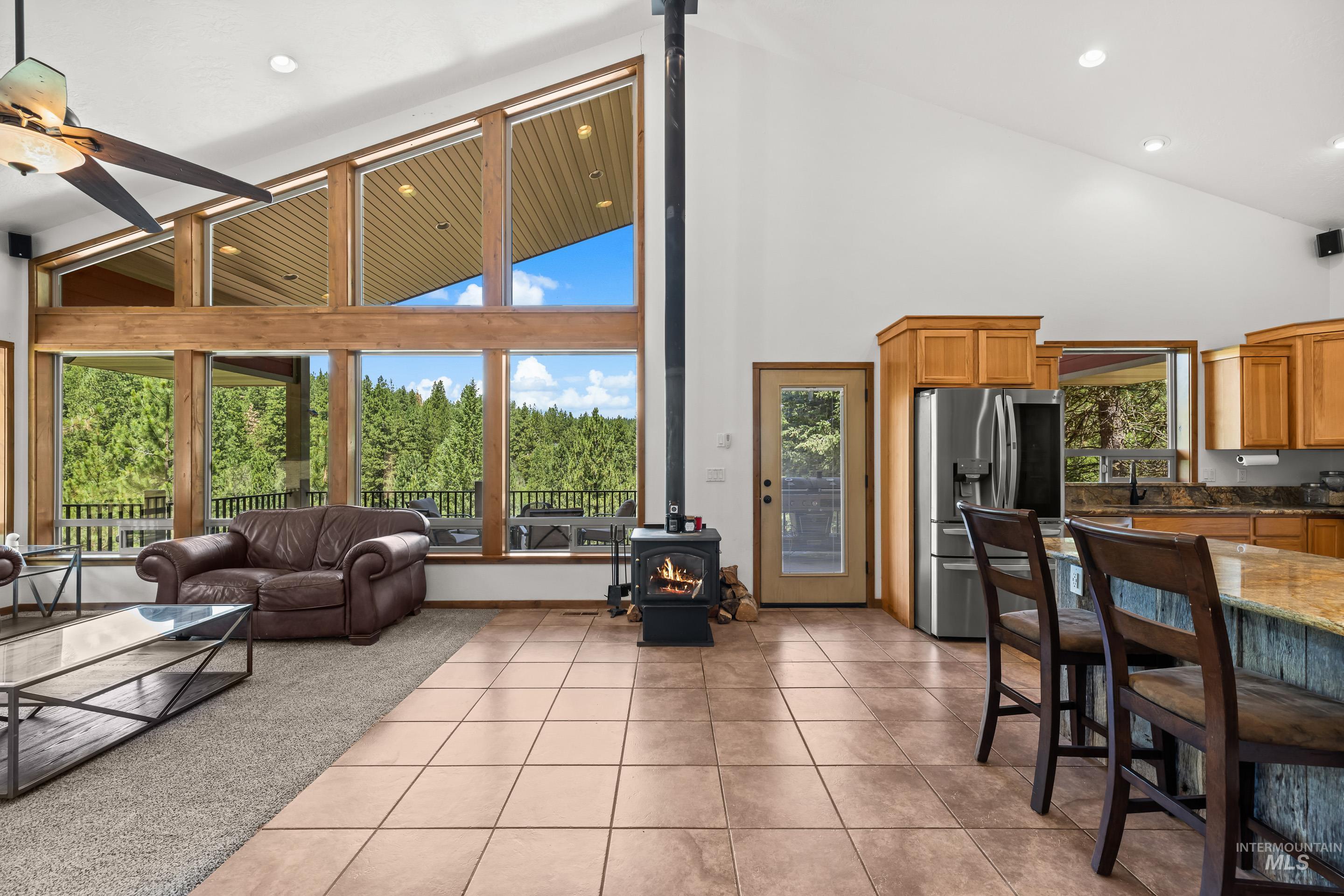 92 Cruickshank Road Horseshoe Bend, ID 83629 - Photo 11 of 50 Great room featuring vaulted ceilings, floor-to-ceiling windows, a central wood-burning stove, and a full kitchen with a breakfast bar