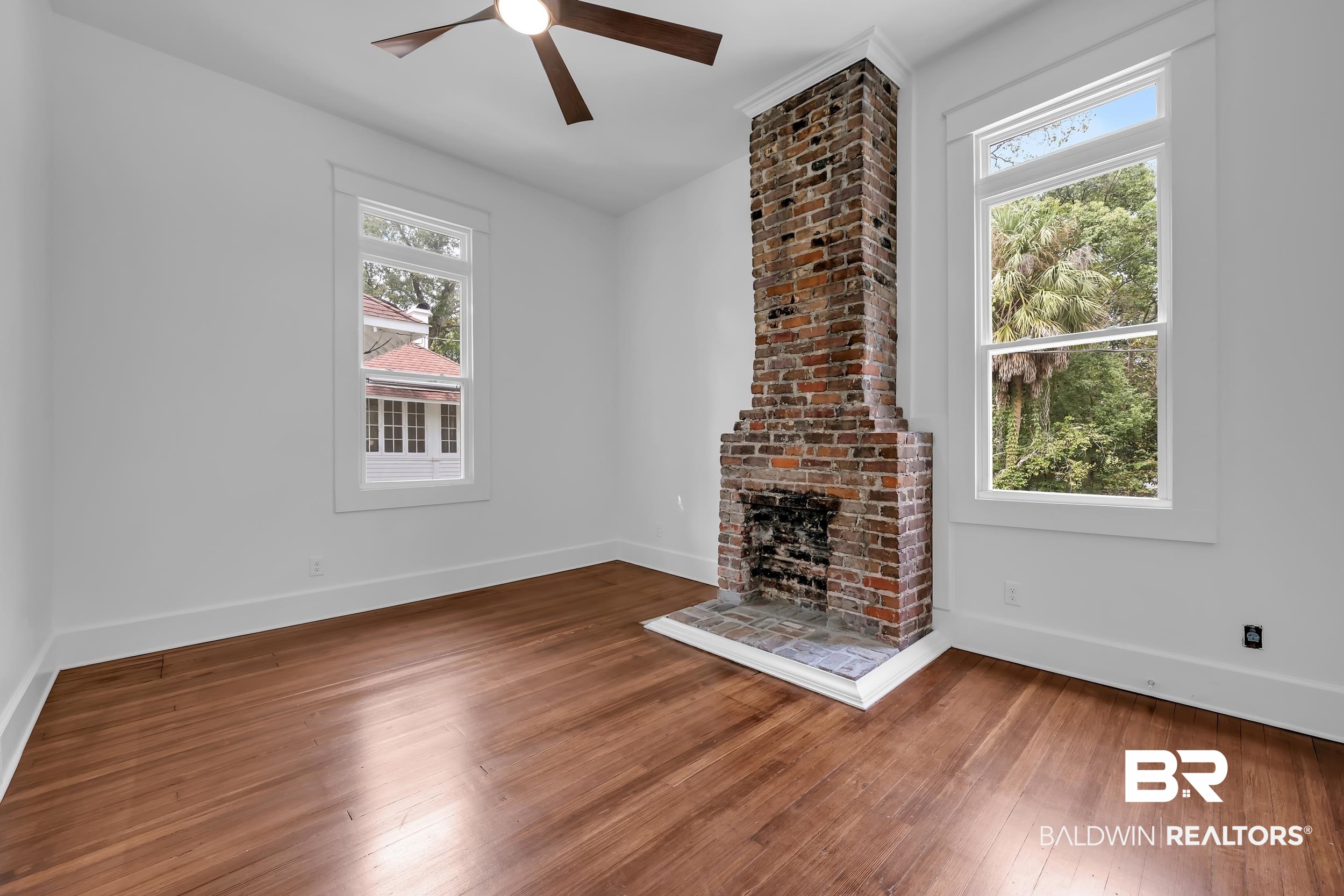1662 Government Street Mobile, AL 36604 - Photo 19 of 33 Unfurnished living room featuring healthy amount of natural light, hardwood / wood-style floors, ceiling fan, and a brick fireplace