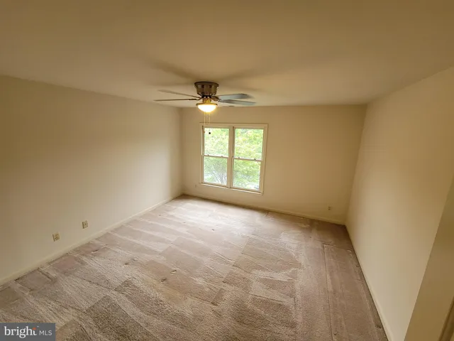 en empty room with windows and chandelier fan