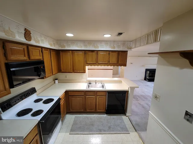 a kitchen with kitchen island stainless steel appliances a sink a stove top oven a counter space and cabinets