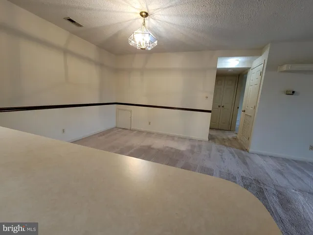 a view of an empty room with a chandelier fan