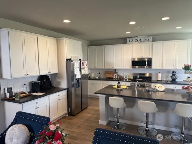 a kitchen with kitchen island granite countertop a stove a sink a refrigerator cabinets and dining table