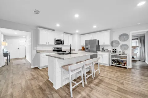 a kitchen with stainless steel appliances granite countertop a stove top oven a sink dishwasher and a refrigerator with wooden floor