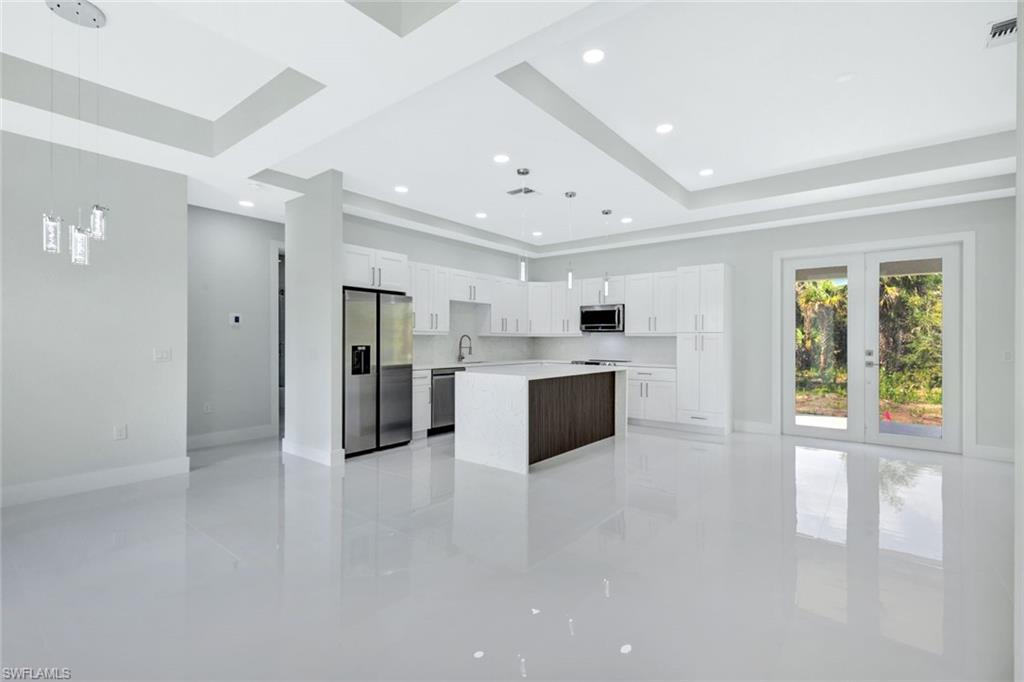 a large white kitchen with a refrigerator a sink dishwasher with a dining table and chairs
