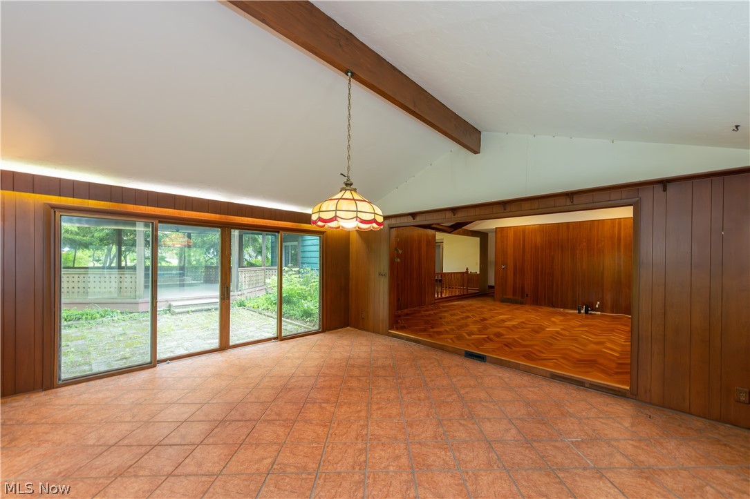 25001 Letchworth Road Beachwood, OH 44122 - Photo 21 of 50 Vaulted ceiling with exposed wood beam, terracotta tile flooring, full-length sliding glass doors, and stained wood paneling