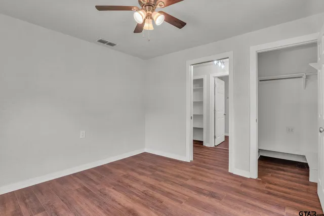 an empty room with wooden floor and ceiling fan