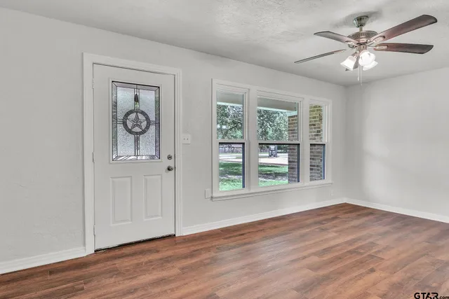 a view of an empty room with a window and wooden floor