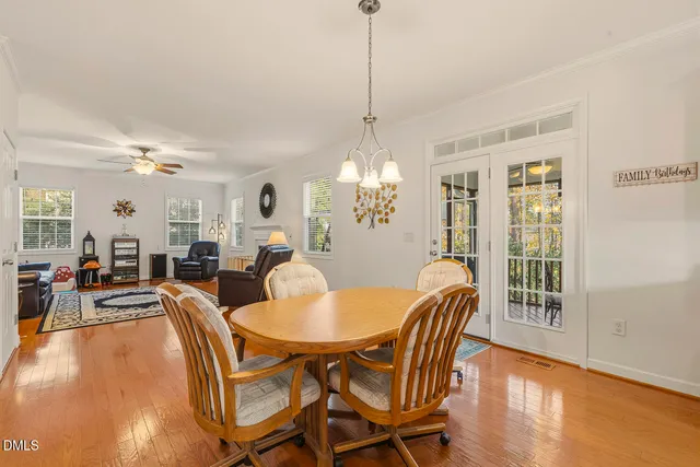 a kitchen with stainless steel appliances granite countertop a stove top oven a sink dishwasher a dining table and chairs with wooden floor