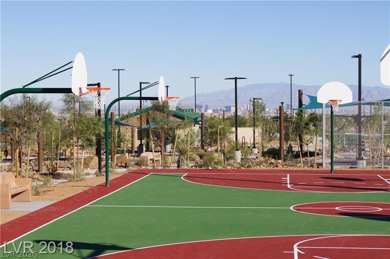 3144 Whitfeild Avenue Henderson, NV 89044 - Photo 38 of 55 An outdoor basketball court beckons, featuring modern hoops and a vibrant green and red surface, set against a distant cityscape.