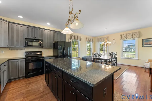 a kitchen with kitchen island granite countertop a stove a sink a refrigerator dining table and chairs