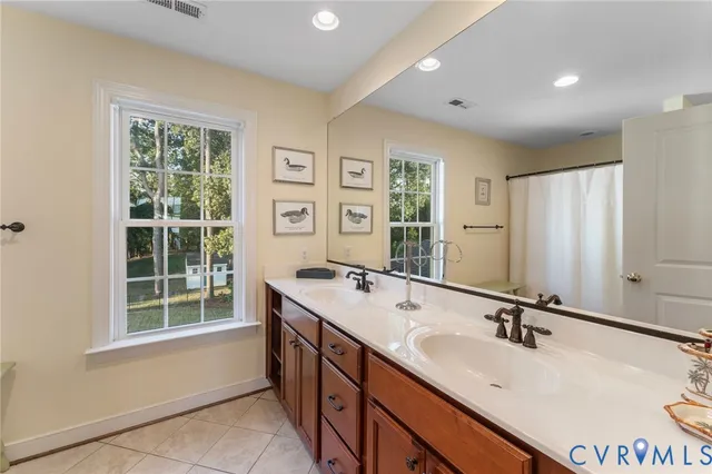 a bathroom with a double vanity sink a mirror and a bathtub