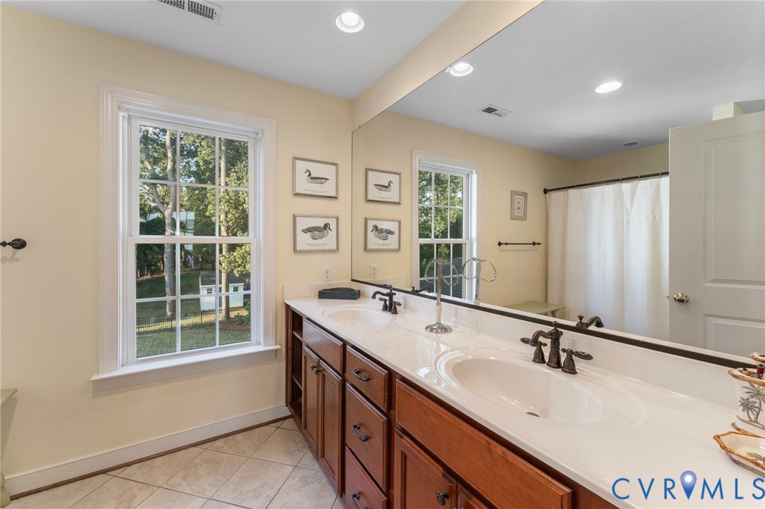 480 Rockingham Road Dunnsville, VA 22454 - Photo 25 of 41 a bathroom with a double vanity sink a mirror and a bathtub