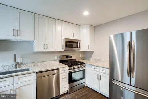 a kitchen with granite countertop white cabinets and sink